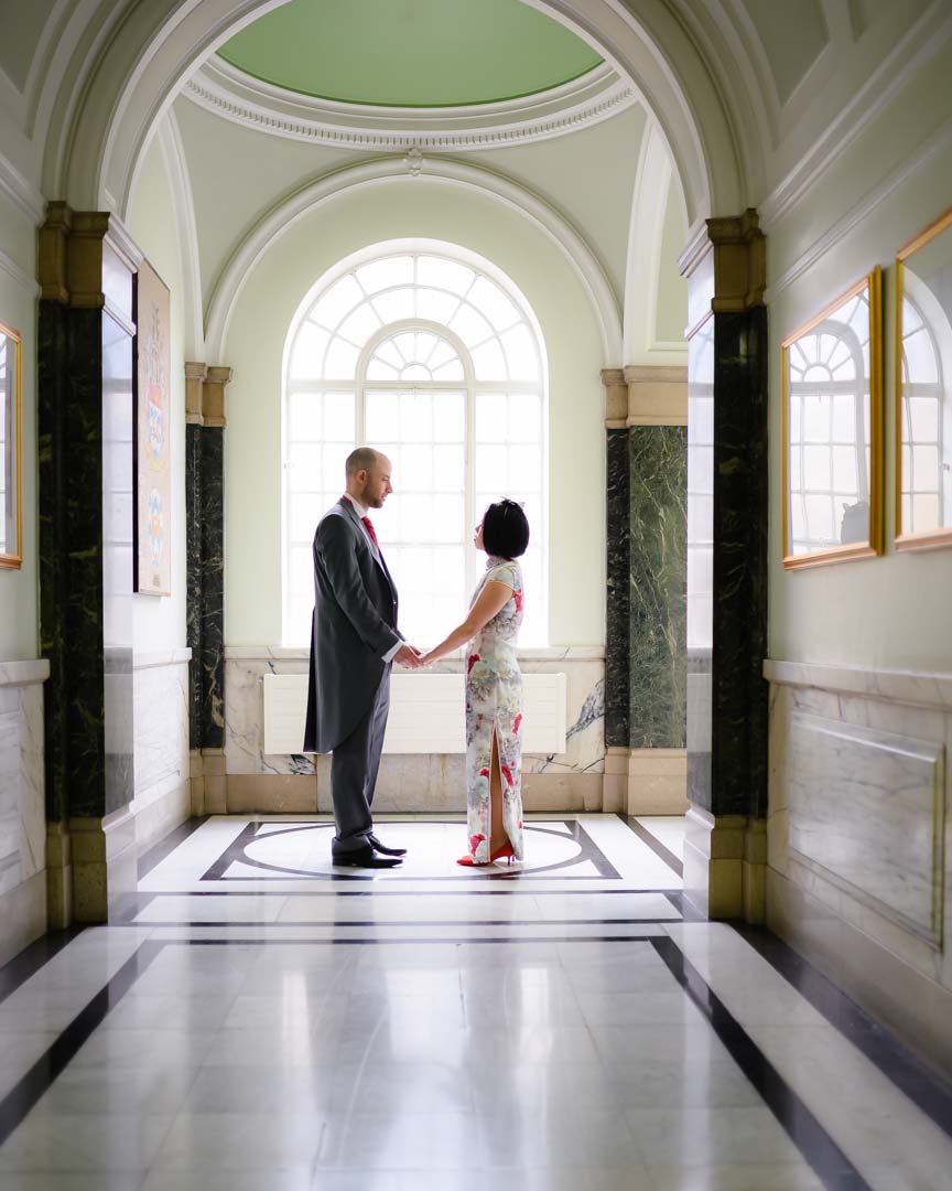 couple holding hands by a window at a wedding