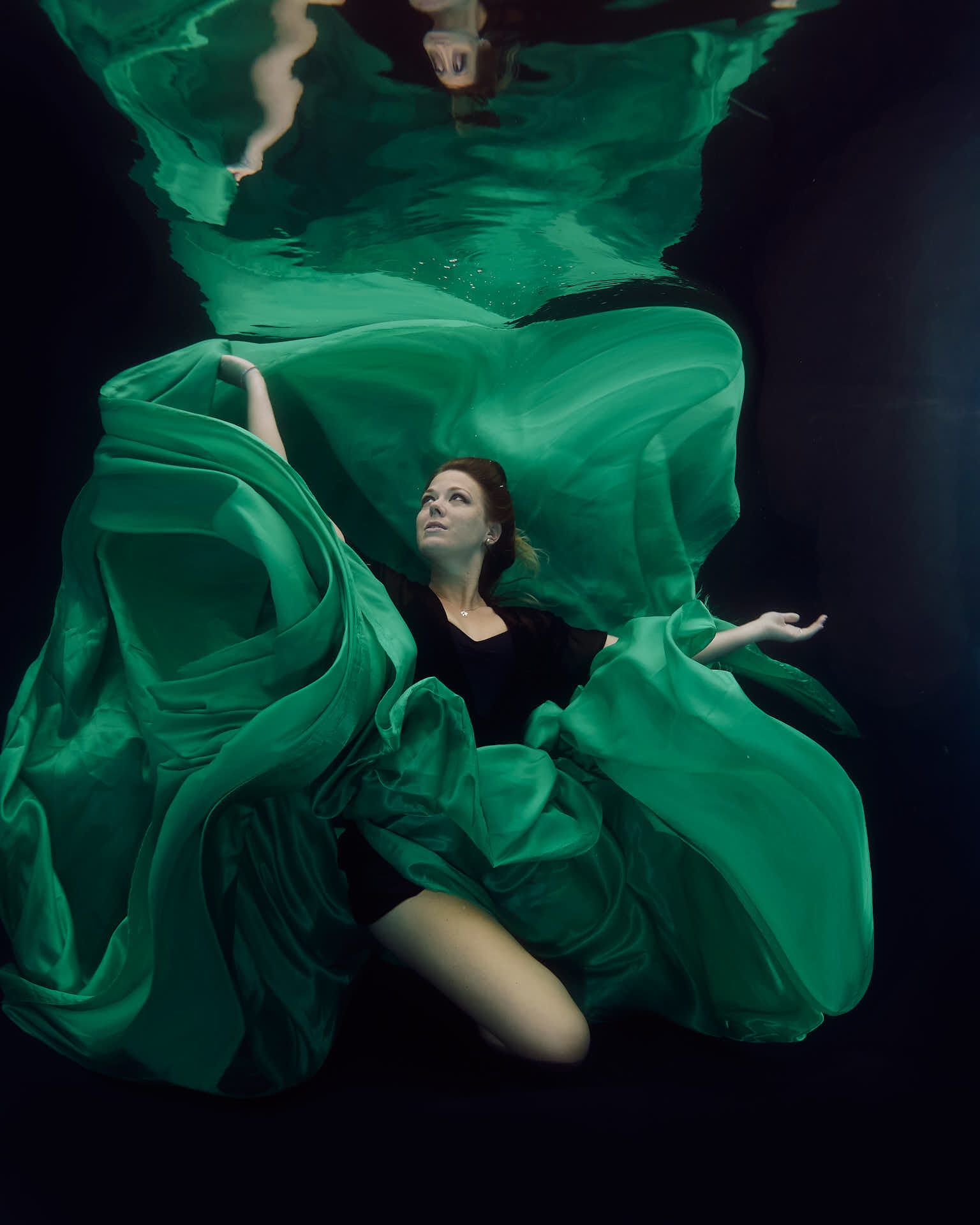 Green satin surrounding a model underwater