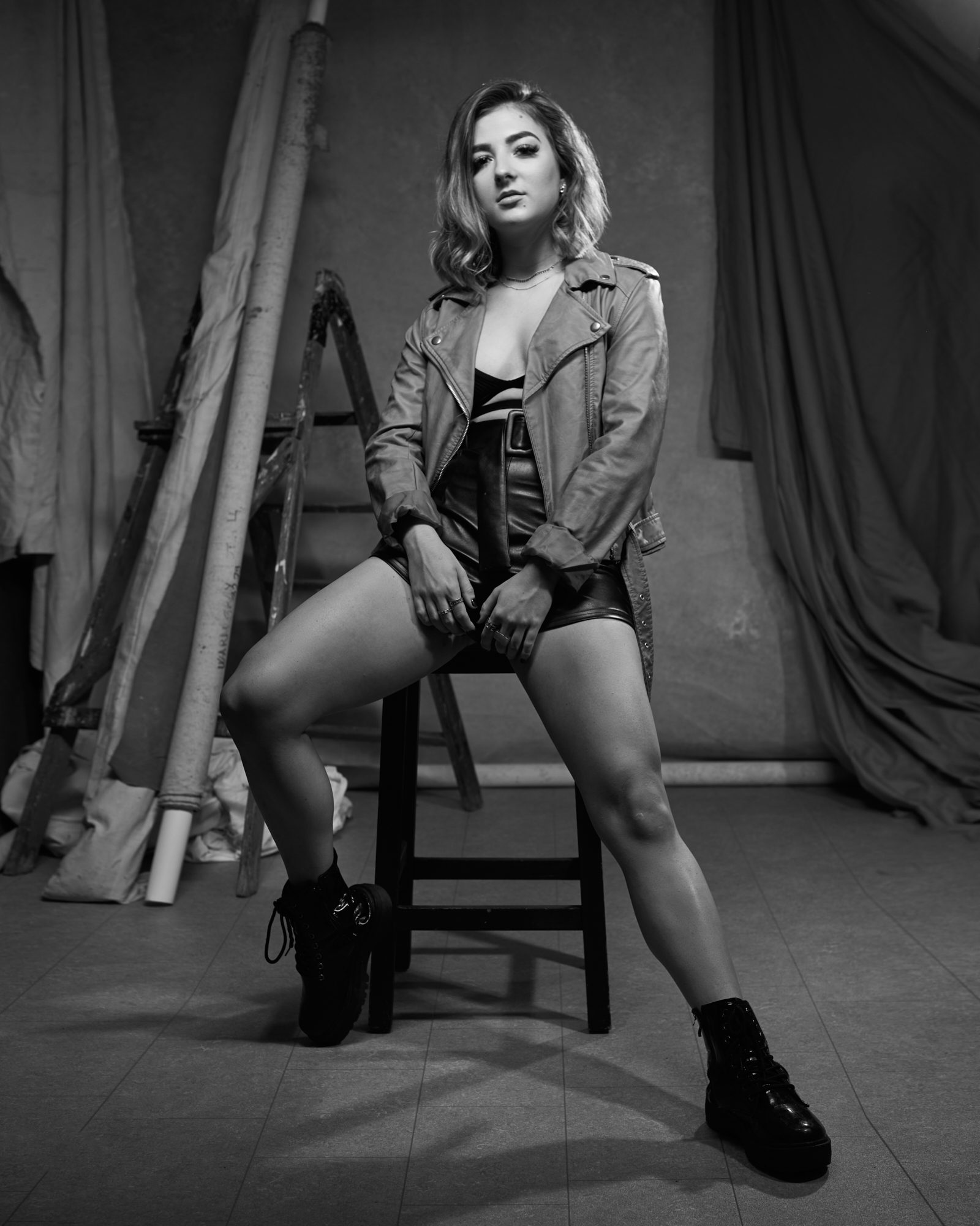 Balck & white image of pretty dancer sat on a stool in leather shorts