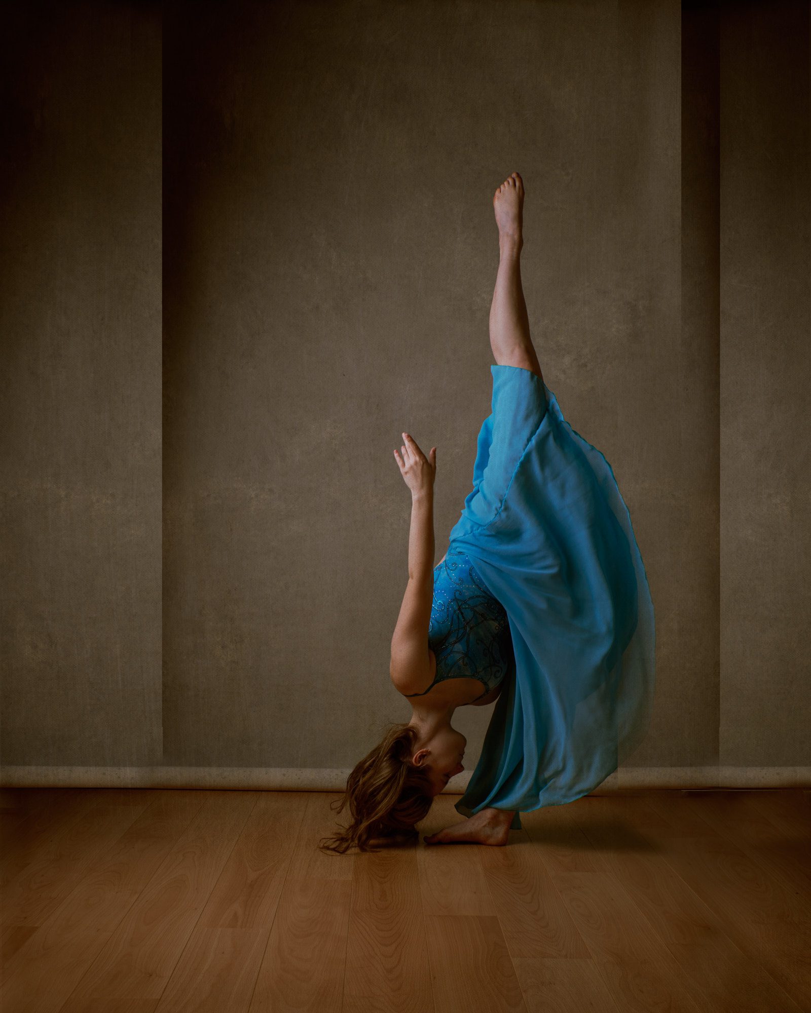 Dancer in a high leg pose wearing a blue dress