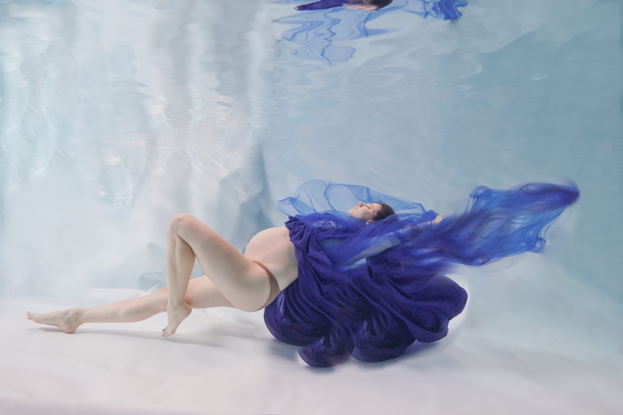 underwater maternity shoot of pregnant lady in a blue dress